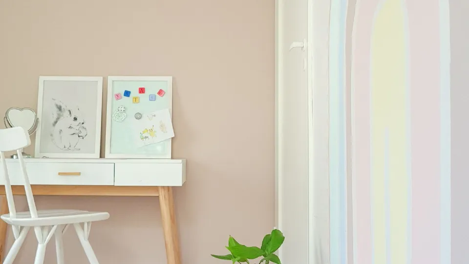 pokój dziecięcy w beżowych kolorach i ze wzorem pastelowej tęczy na ścianie