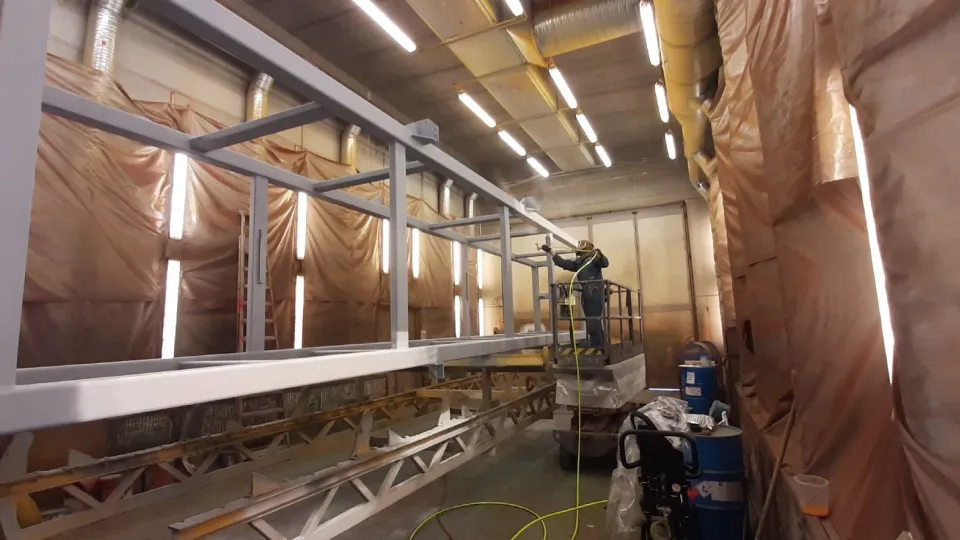 Mężczyźni malujący metalowe konstrukcje.