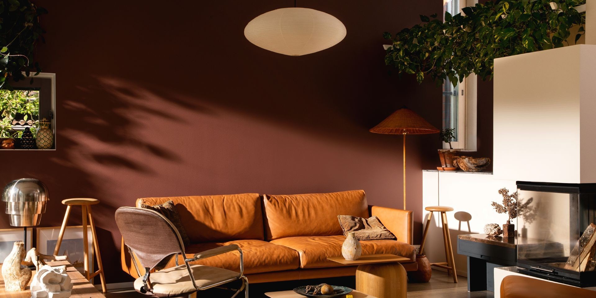  przytulny salon ze ścianą w kolorze ziemistego brązu i skórzaną sofą w odcieniu ciepłego brązu