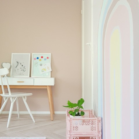pokój dziecięcy w beżowych kolorach i ze wzorem pastelowej tęczy na ścianie