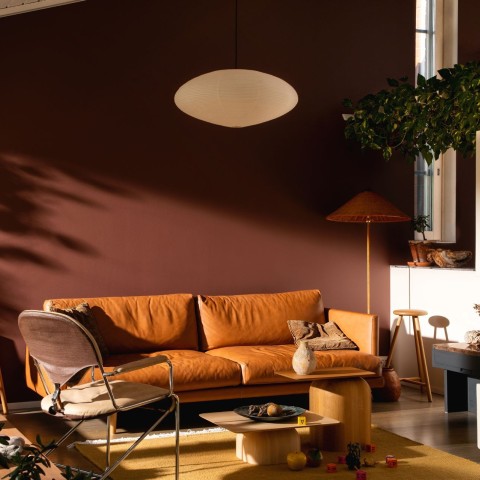 przytulny salon ze ścianą w kolorze ziemistego brązu i skórzaną sofą w odcieniu ciepłego brązu