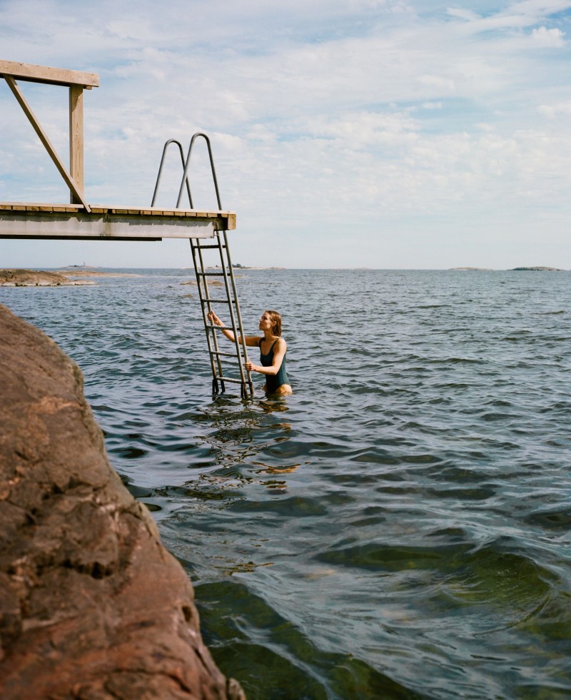 kobieta pływająca w morzu w pobliżu kamienistej plaży