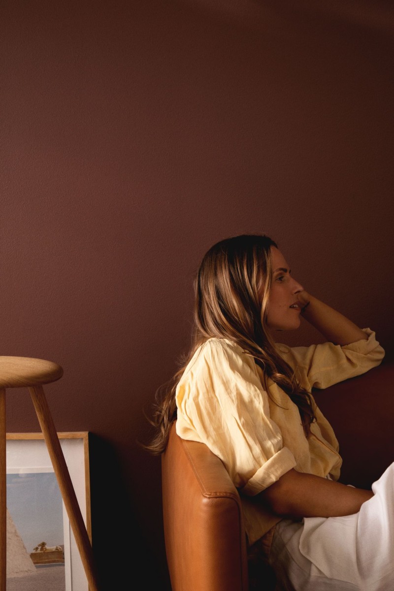 kobieta siedząca na kanapie naprzeciwko ściany w kolorze ciepłego brązu