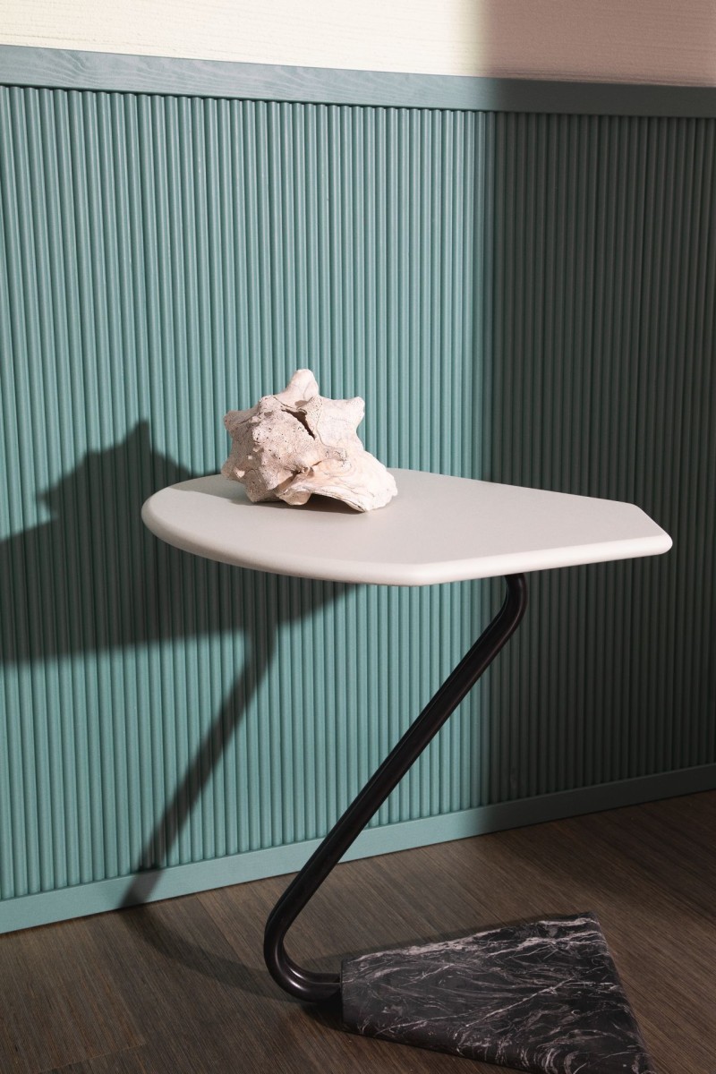 minimalistyczny mały biały stolik przed niebiesko-zieloną boazerią 