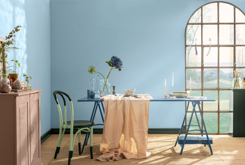 ściana w kolorze błękitnym oraz stół z krzesłami