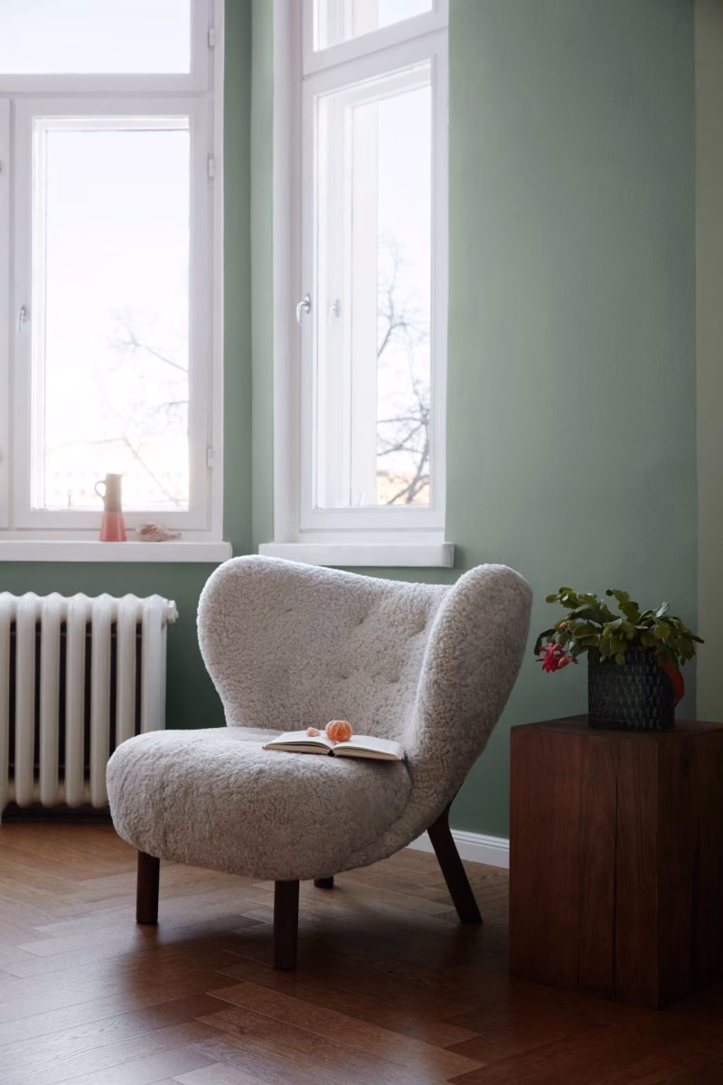 ściany salonu w delikatnej zieleni i fotel z lat 70.