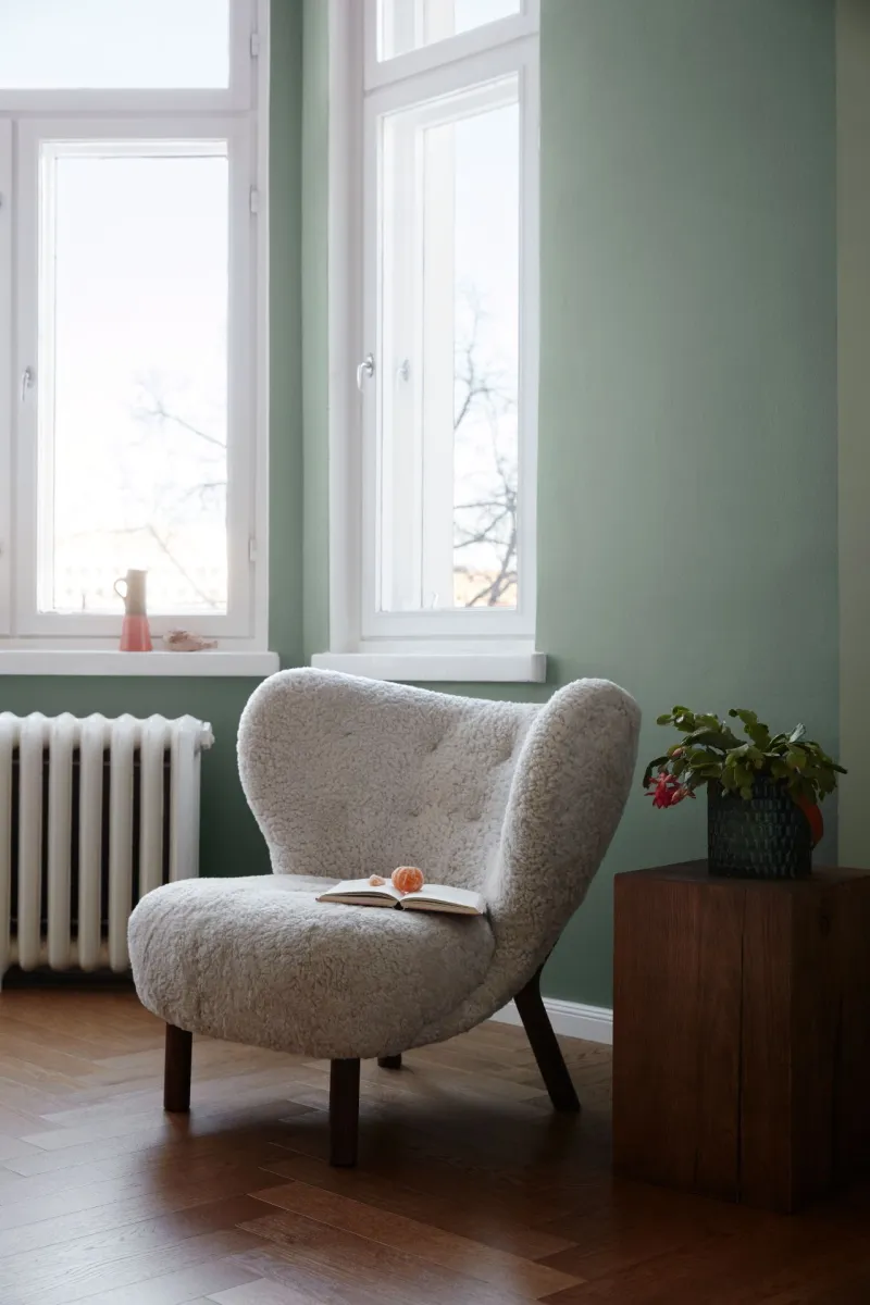 ściany salonu w delikatnej zieleni i fotel z lat 70.