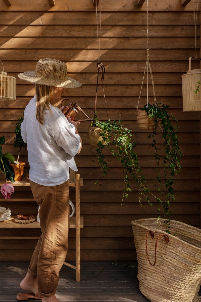 kobieta podlewa rośliny w pergoli 